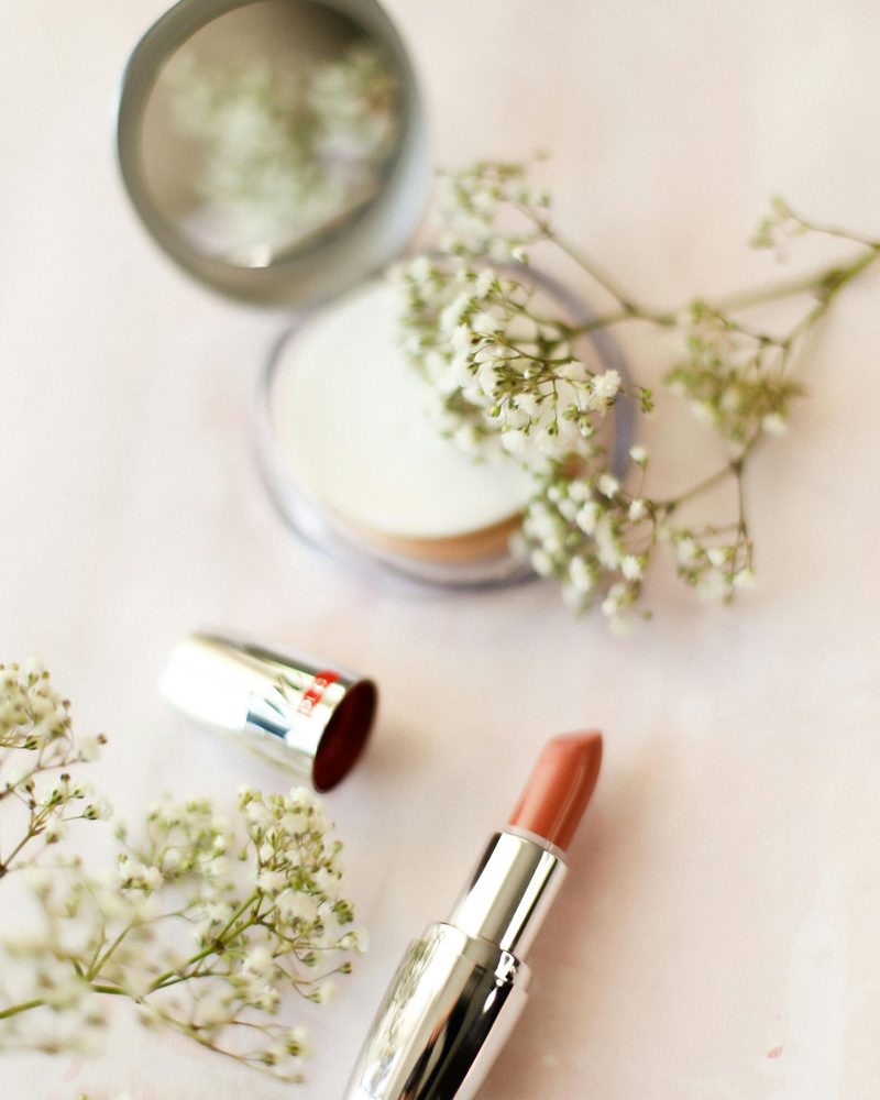 Nude lipstick and beauty essentials in editorial flatlay
